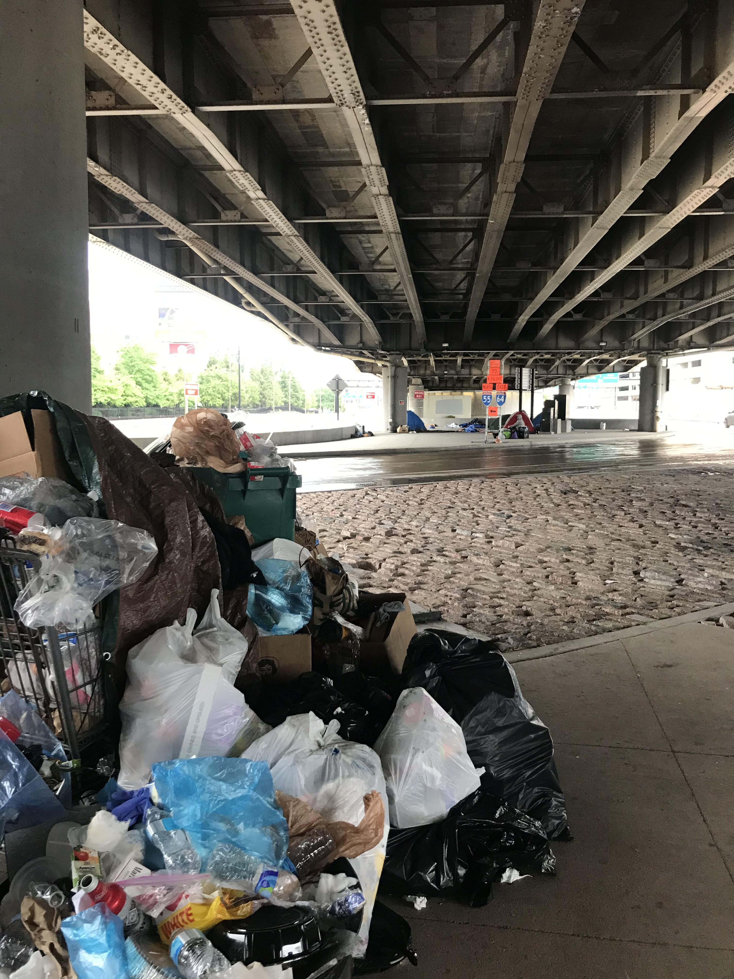 Residents make their best attempt to collect trash in the I-44 encampment, for which the city has refused to provide a dumpster.