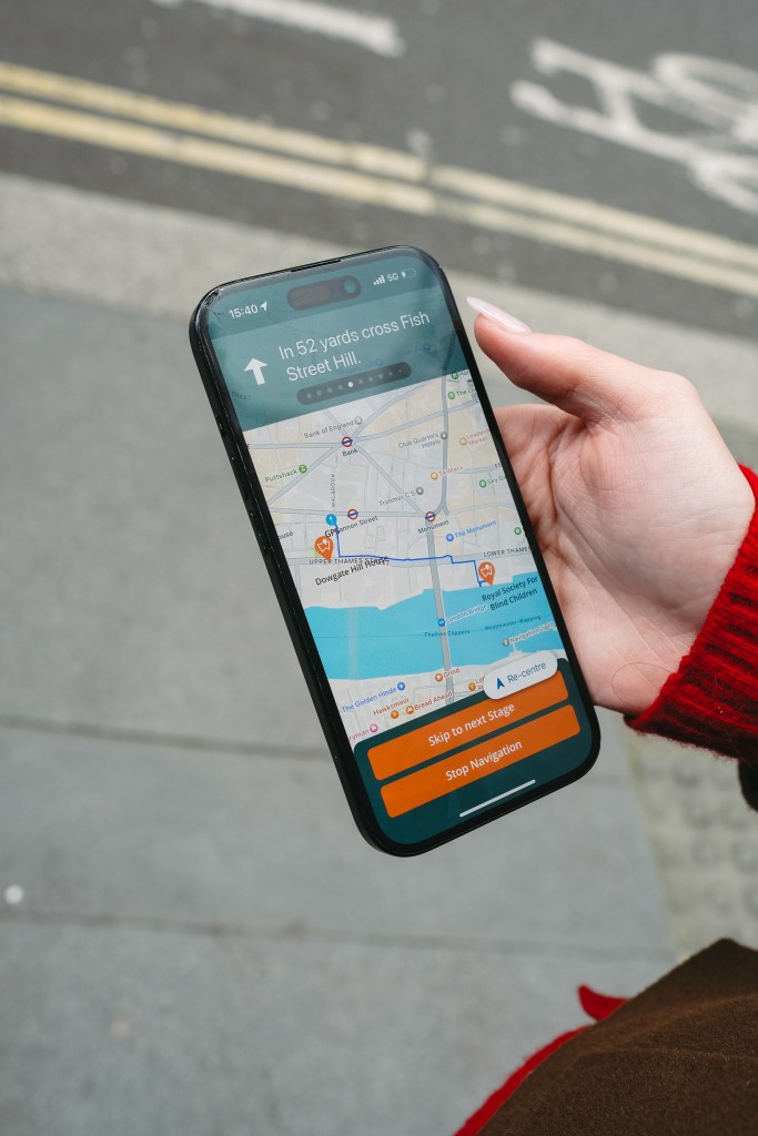 Image description: a hand holds a cell phone displaying a screen from the Waymap app. 